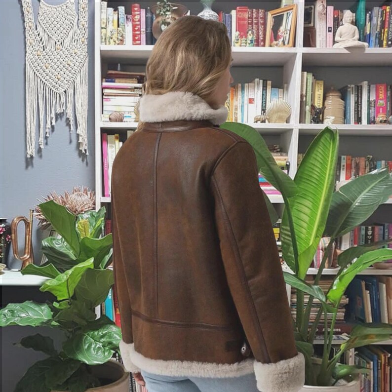 Woman wearing brown aviator jacket at home