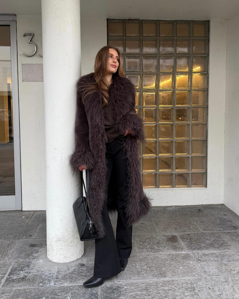 Long suede coat with shaggy trim at hem worn with flared trousers